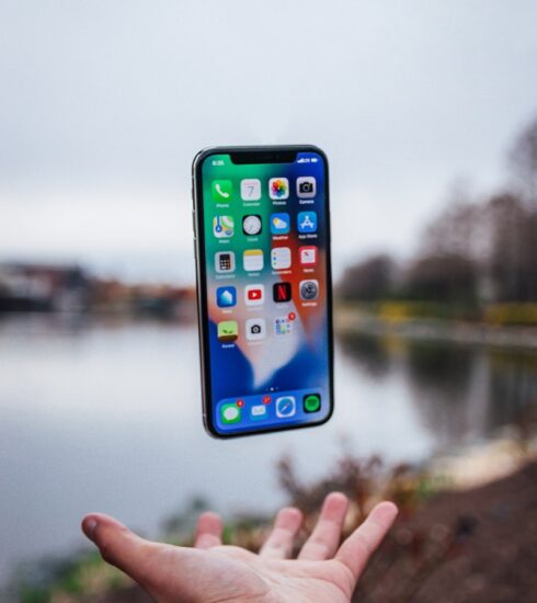 silver iPhone X floating over open palm